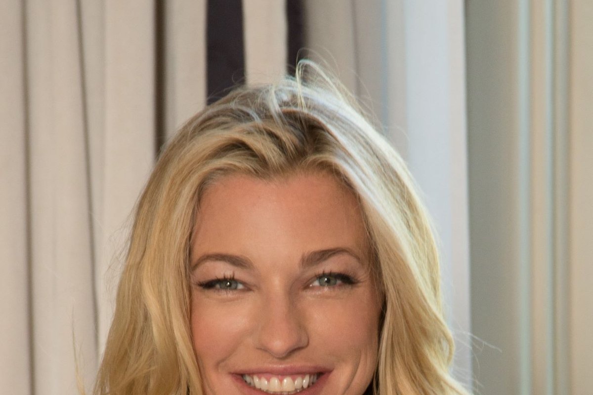 Nicole Junkermann sorride in un ritratto ravvicinato, con i capelli biondi sciolti, davanti a tende chiare